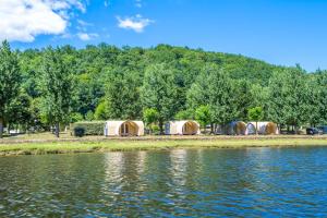 a row of tents next to a body of water at Camping Le château du gibanel in Saint-Martial-Entraygues
