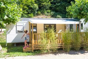 a woman standing on the porch of a tiny house at Camping Le château du gibanel in Saint-Martial-Entraygues