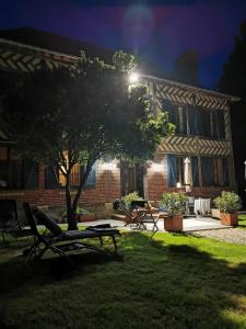 una casa con un árbol en el patio por la noche en Le Domaine des Volets bleus, en Beuzeville