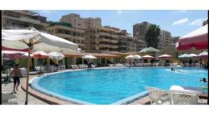 a large swimming pool with chairs and umbrellas at Family Condo With Panoramic Sea View 1 in Alexandria