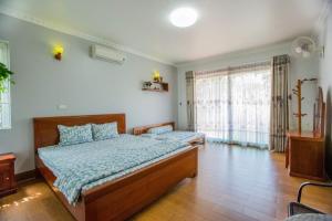 a bedroom with two beds and a large window at Airi Villas Ba Vì Venue Travel in Ba Vì