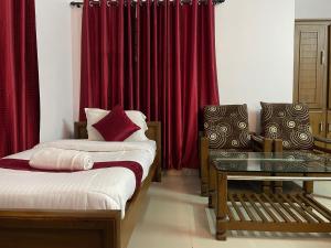 two beds in a room with red curtains at Hotel Caveri in Madikeri