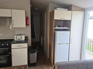 a kitchen with white cabinets and a refrigerator at The orchards holiday home in Clacton-on-Sea