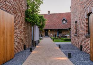 een steegje tussen twee bakstenen gebouwen met een pad bij Hoeve Roosbeek in Zepperen