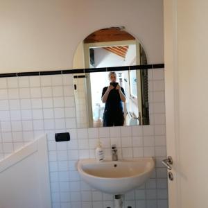 une femme prenant une photo d'elle-même dans un miroir de bain dans l'établissement Locazione turistica la casetta, à Conegliano
