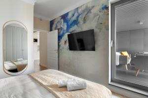 a bedroom with a large mirror and a tv on the wall at Elite Apartments Granaria The View in Gdańsk