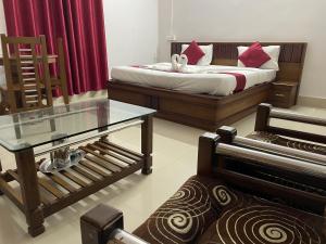 a bedroom with a bed with red curtains and a glass table at Hotel Caveri in Madikeri