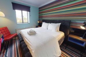 a hotel room with a bed with a striped wall at Village Hotel Birmingham Walsall in Walsall