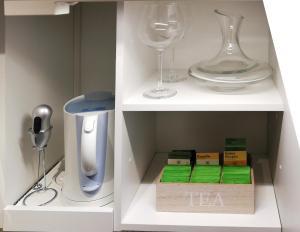 un armario blanco con copas de vino y set de té en Lebensfreude Appartement, en Bad Goisern