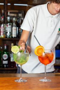 um chef a preparar três cocktails num bar em Le Corti Di Montepitti em Suvereto