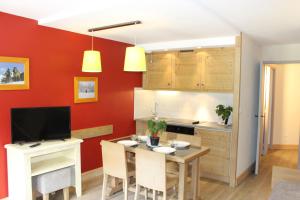 eine Küche mit roten Wänden und einem Tisch mit Stühlen in der Unterkunft Résidence Christiana 406 Clés Blanches Courchevel in La Tania