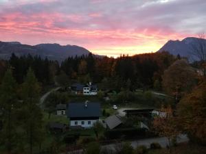 a house in the mountains with a sunset in the background at Lebensfreude Appartement in Bad Goisern