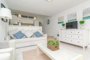 a white living room with a couch and a tv at Ca'n Opus 321 in Port d'Alcudia