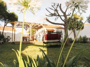 a garden with a bench in a yard with a tree at Hospedium Hostel República Surf House in Ericeira