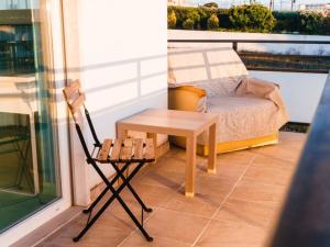 a patio with a table and a chair on a balcony at Hospedium Hostel República Surf House in Ericeira