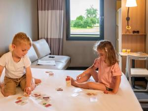 聖喬治得戈的住宿－宜必思彭托森灣聖米歇爾山酒店，两个孩子坐在床上玩拼图