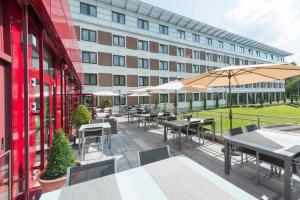 un patio al aire libre con mesas y sombrillas frente a un edificio en Parc Hotel Alvisse, en Luxemburgo