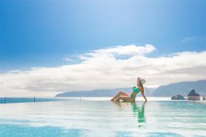 a woman sitting in the water in a infinity pool at Aqua Natura Bay in Porto Moniz