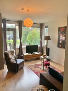 a living room with a couch and a tv at Bed and Breakfast De Paalberg in Hoenderloo