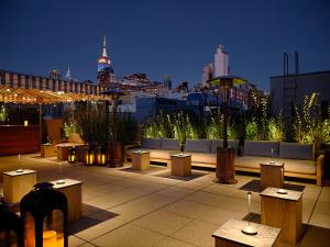 eine Dachterrasse mit Tischen und Bänken und einer Skyline der Stadt in der Unterkunft The Moore in New York