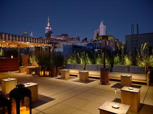 a rooftop patio with tables and benches and a city skyline at The Moore in New York