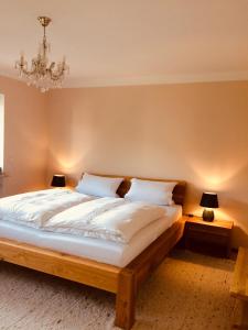 1 dormitorio con 1 cama grande y lámpara de araña en Charmantes Garten-Apartment: Erholung im Chiemgau, en Unterwossen