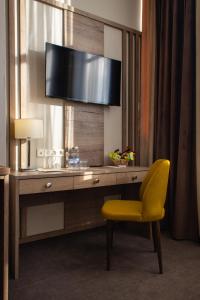 uma secretária num quarto de hotel com uma cadeira amarela em HELIOPARK Residence em Penza