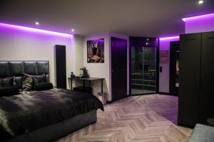 a bedroom with purple lighting and a bed and a desk at Royal Suite in 's-Gravenzande