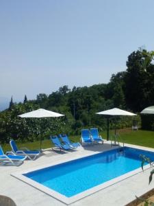 una piscina con sillas y sombrillas azules en Apartment Rea with Pool, en Brseč