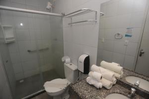 a bathroom with a toilet and a sink with towels at Rede Andrade Navegantes in Recife