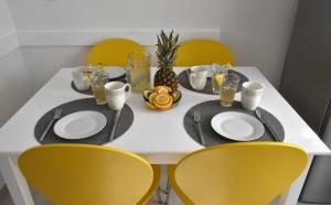 Apartment Meryl في Mravince: طاولة بيضاء مع كراسي صفراء وطاولة مع صحون وطعام