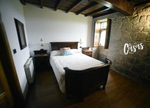 1 dormitorio con cama y pared de piedra en As Casas Ribeira Sacra, en Chantada