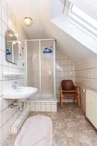 a bathroom with a sink and a shower and a chair at Ferienwohnungen im Landhaus Oldenhof in Stedesdorf