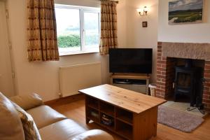 a living room with a television and a fireplace at The Cottage, Poplars Farm in Ashbourne
