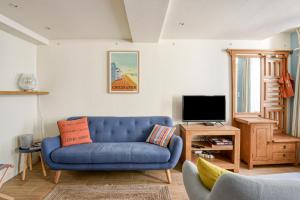 a living room with a blue couch and a tv at Sea You Soon in Langrune-sur-Mer