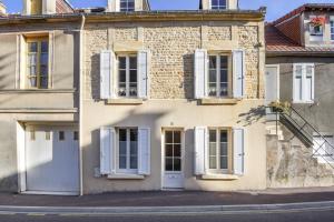 a building with white shutters and a door at Sea You Soon in Langrune-sur-Mer