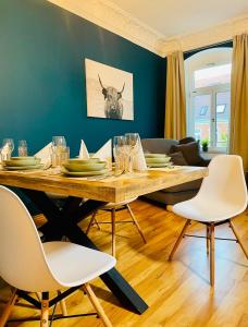 a dining room with a wooden table and white chairs at Edle Ferienwohnung - Industrial Style in Dresden