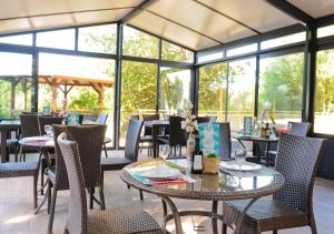 ein Restaurant mit Tischen, Stühlen und Fenstern in der Unterkunft Camping Le Paradis in Talmont