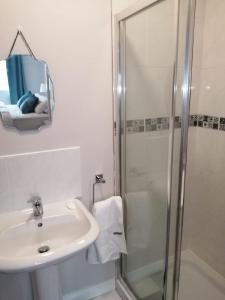 La salle de bains blanche est pourvue d'un lavabo et d'une douche. dans l'établissement Apt 1, Whiterocks Portrush, à Portrush