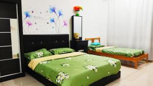 1 Schlafzimmer mit 2 Betten mit grüner Bettwäsche und Blumen in der Unterkunft Mevin Woodsbury Home Butterworth Penang in Butterworth