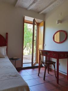 a bedroom with a bed and a desk and a window at Quinta do Rio in Vale do Serrão