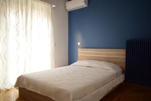 a bedroom with a bed with a blue wall and a window at Beautiful Renovated Flat in Athens (The Dem Flat) in Athens