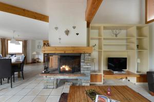 a living room with a fireplace and a tv at Goélia Les Chalets des Deux Domaines in Peisey-Nancroix