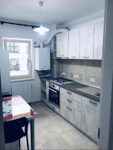 a kitchen with white cabinets and a stove and a table at Conest Studio in Iaşi