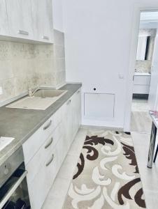 a kitchen with white cabinets and a sink and a rug at Conest Studio in Iaşi