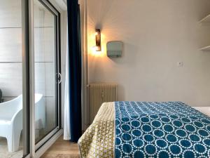 - une chambre avec un lit bleu et blanc et une fenêtre dans l'établissement Triangle d’or, à Le Touquet-Paris-Plage
