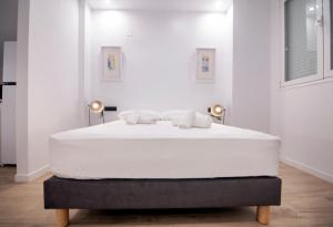 een wit bed in een witte kamer met 2 lampen bij VLC Host - Mercat Central in Valencia