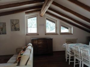 a dining room with a table and chairs and windows at Casa Leonilla in Pellizzano