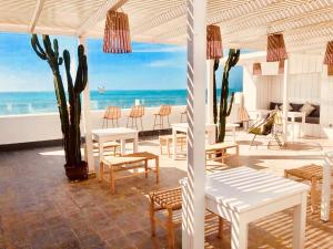 a patio with tables and chairs and the beach at Hostel La Smala in Essaouira