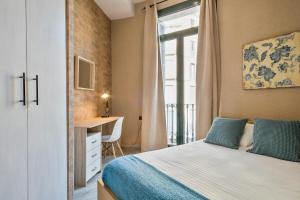 1 dormitorio con cama, escritorio y ventana en Midtown Luxury Apartments by Sweet Inn, en Barcelona